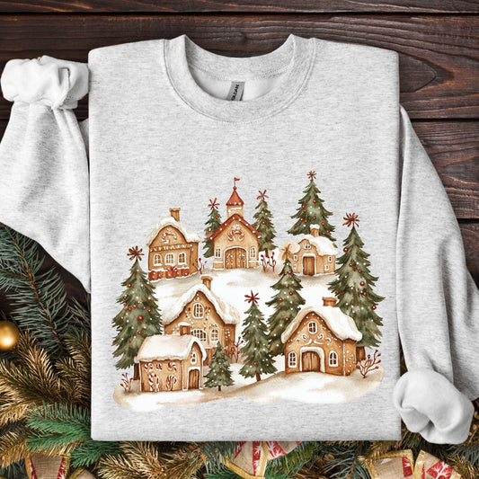 Ash gray Gildan sweatshirt with a watercolor snowy gingerbread village and evergreen trees design.