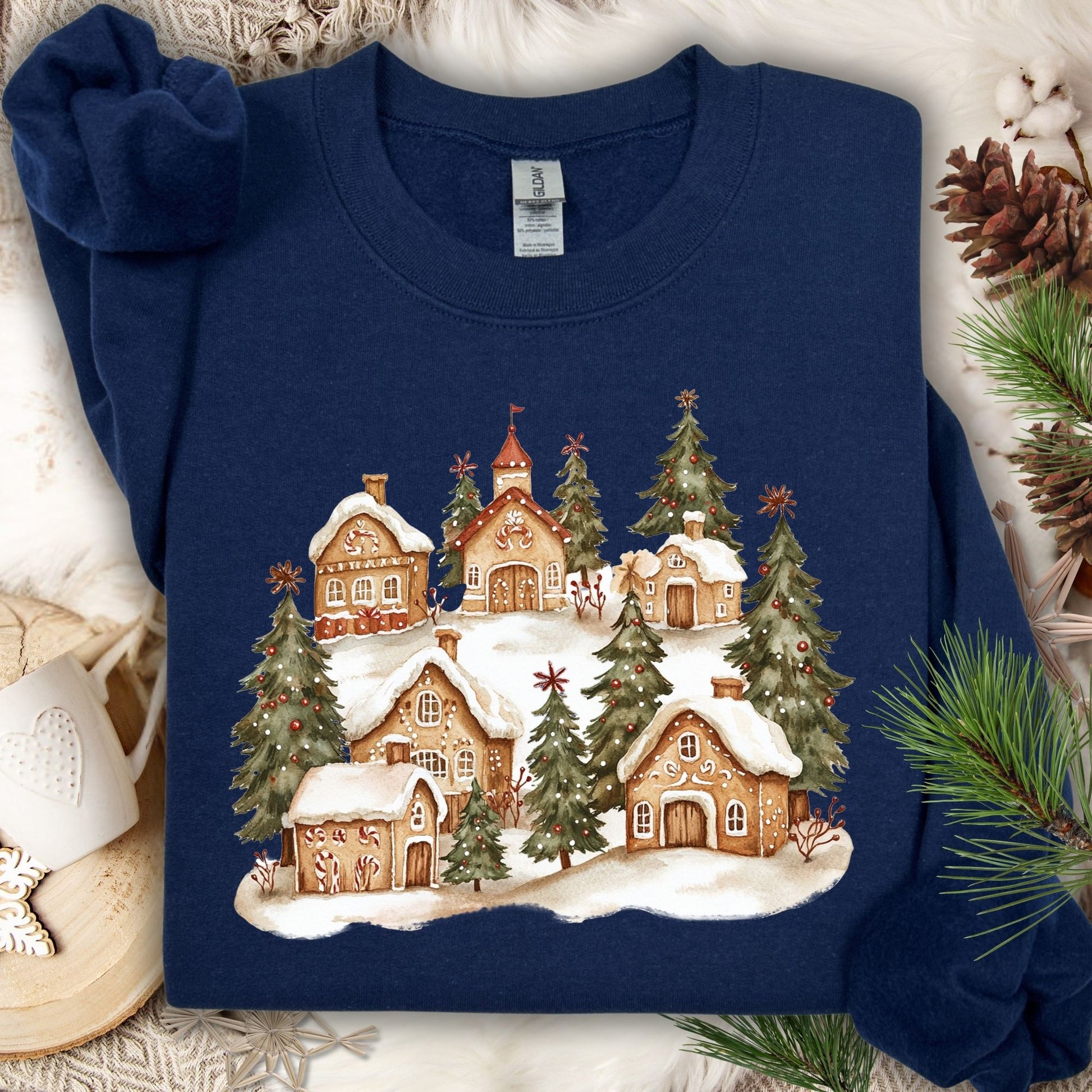 Navy Gildan sweatshirt with a watercolor snowy gingerbread village and evergreen trees.