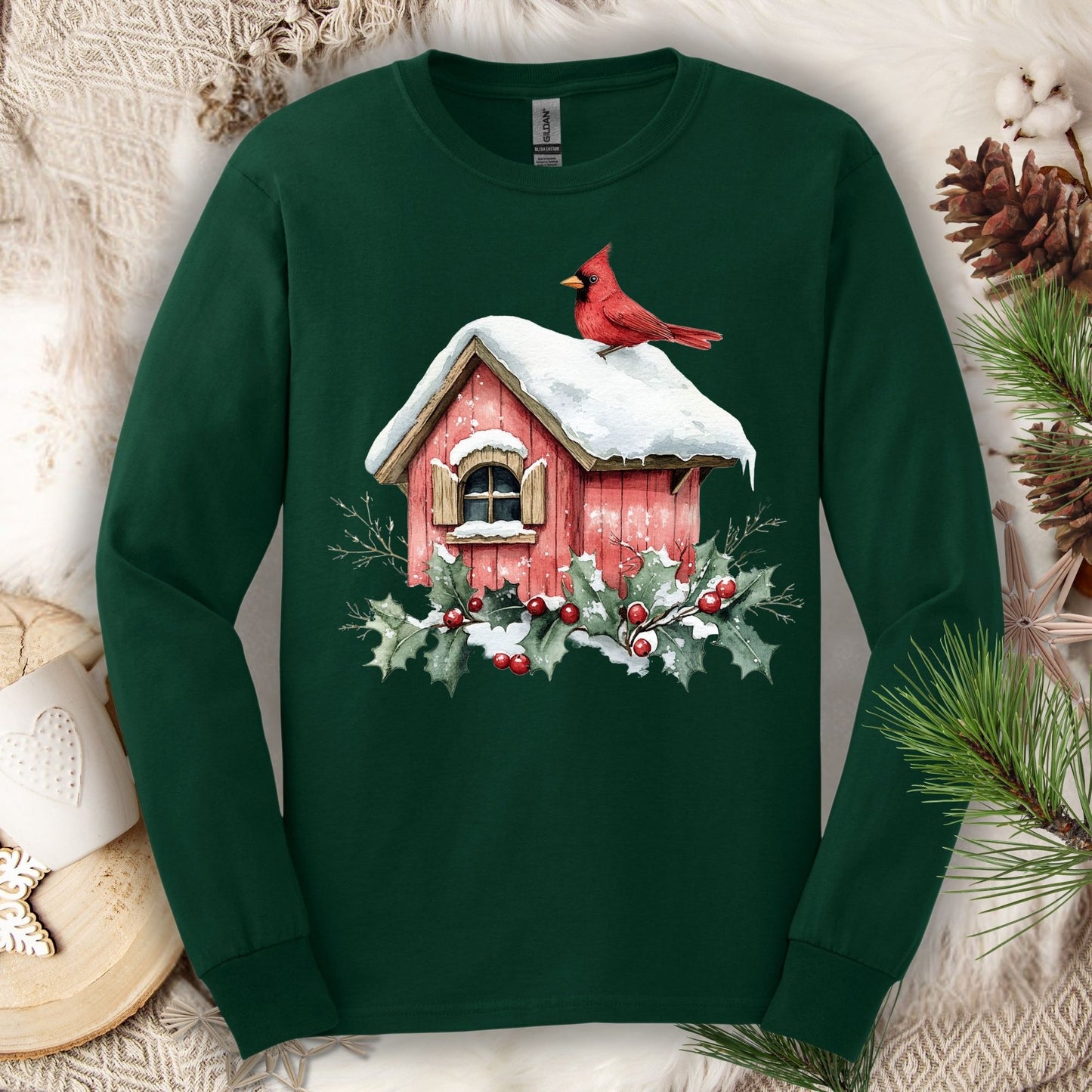 Forest Green long sleeve tee with a watercolor red cardinal on a snowy rustic birdhouse with holly.