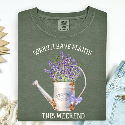 Moss green "Sorry, I Have Plants This Weekend" tee with a vintage watering can and lavender.