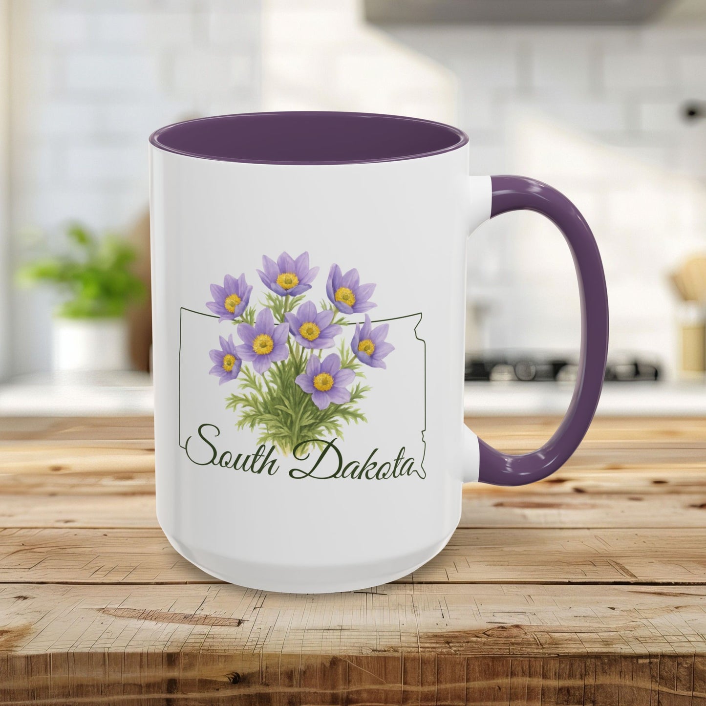 White 15oz ceramic mug with purple interior and handle, featuring a watercolor American Pasque flower bouquet and "South Dakota" script over a state outline.