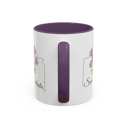 White ceramic mug with purple interior and handle, featuring a watercolor pasque flower and "South Dakota" script.