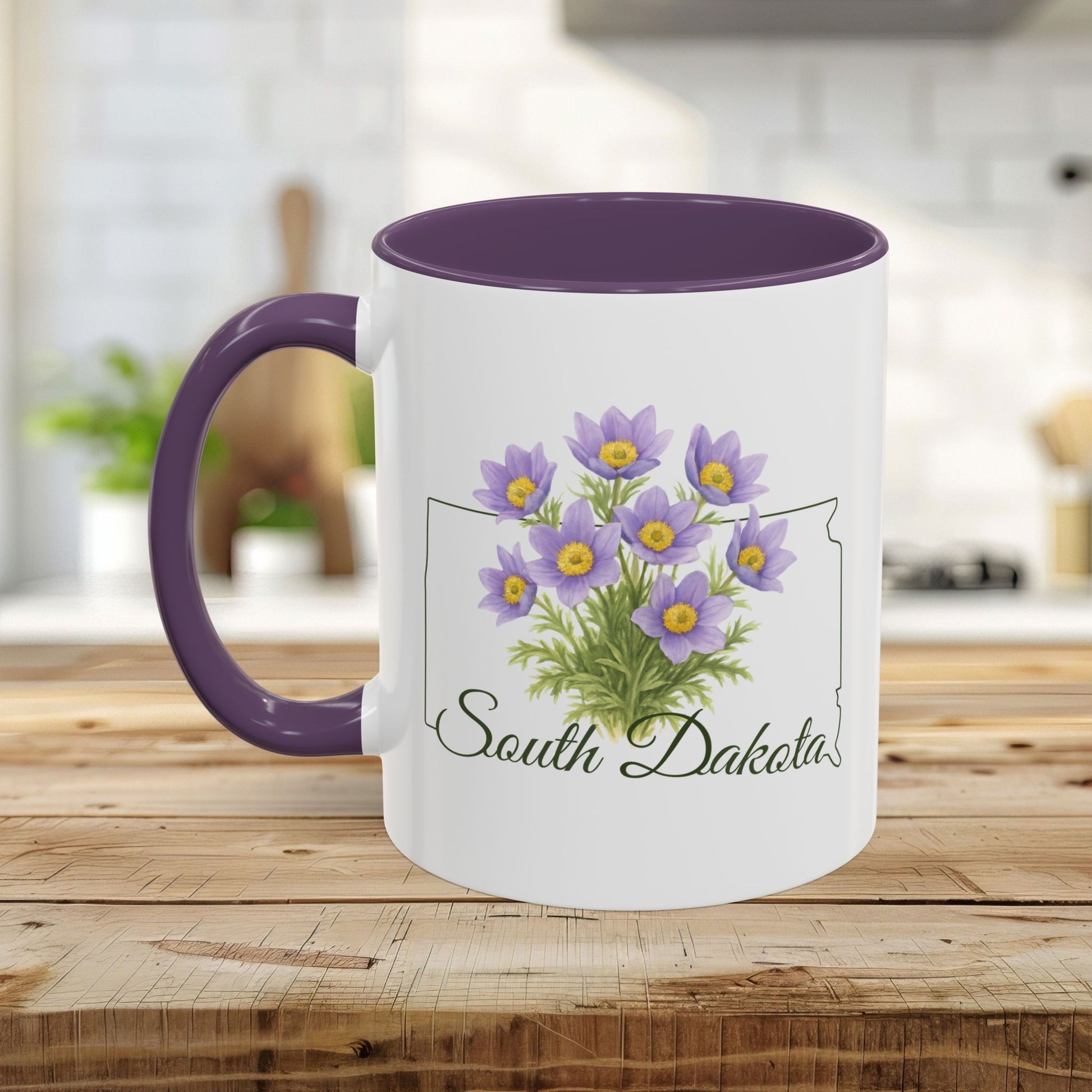 White ceramic mug with purple interior and handle, featuring a watercolor American Pasque flower bouquet over a South Dakota outline.