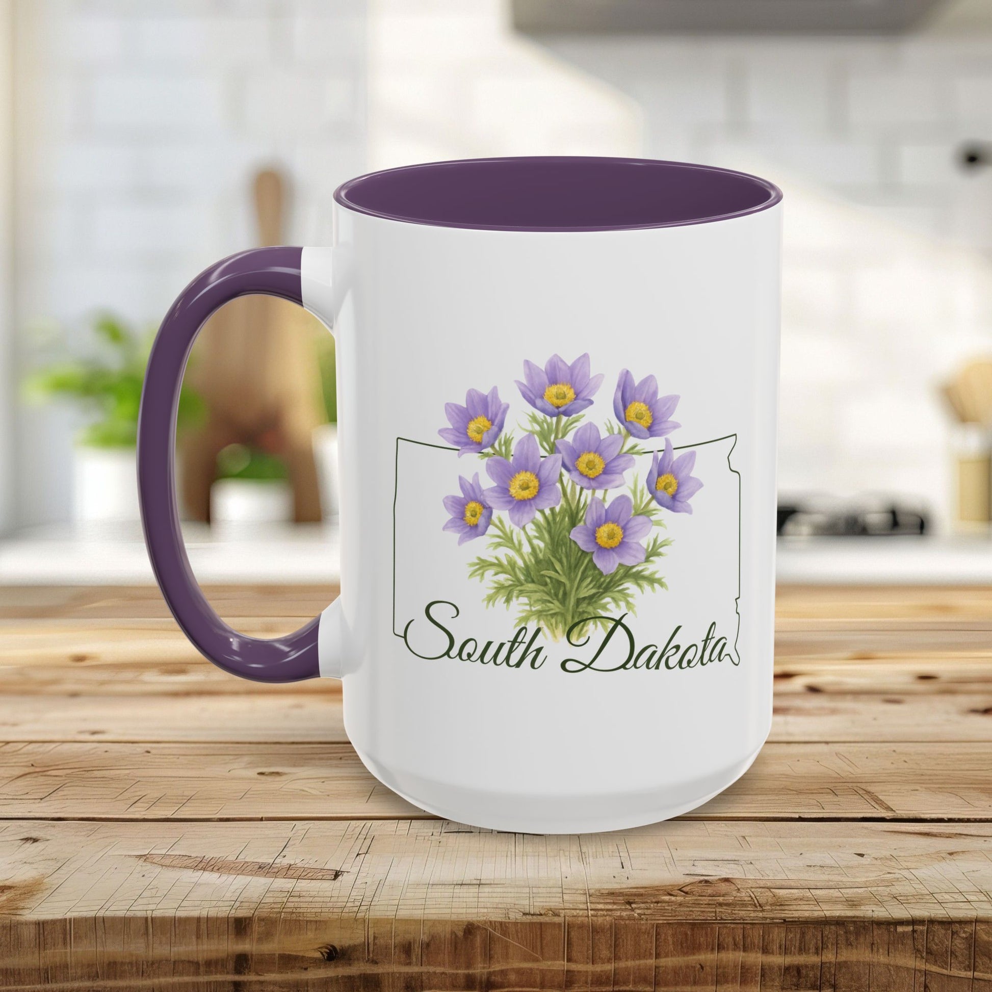 White ceramic mug with purple interior and handle, featuring a watercolor American Pasque flower bouquet over a South Dakota outline.