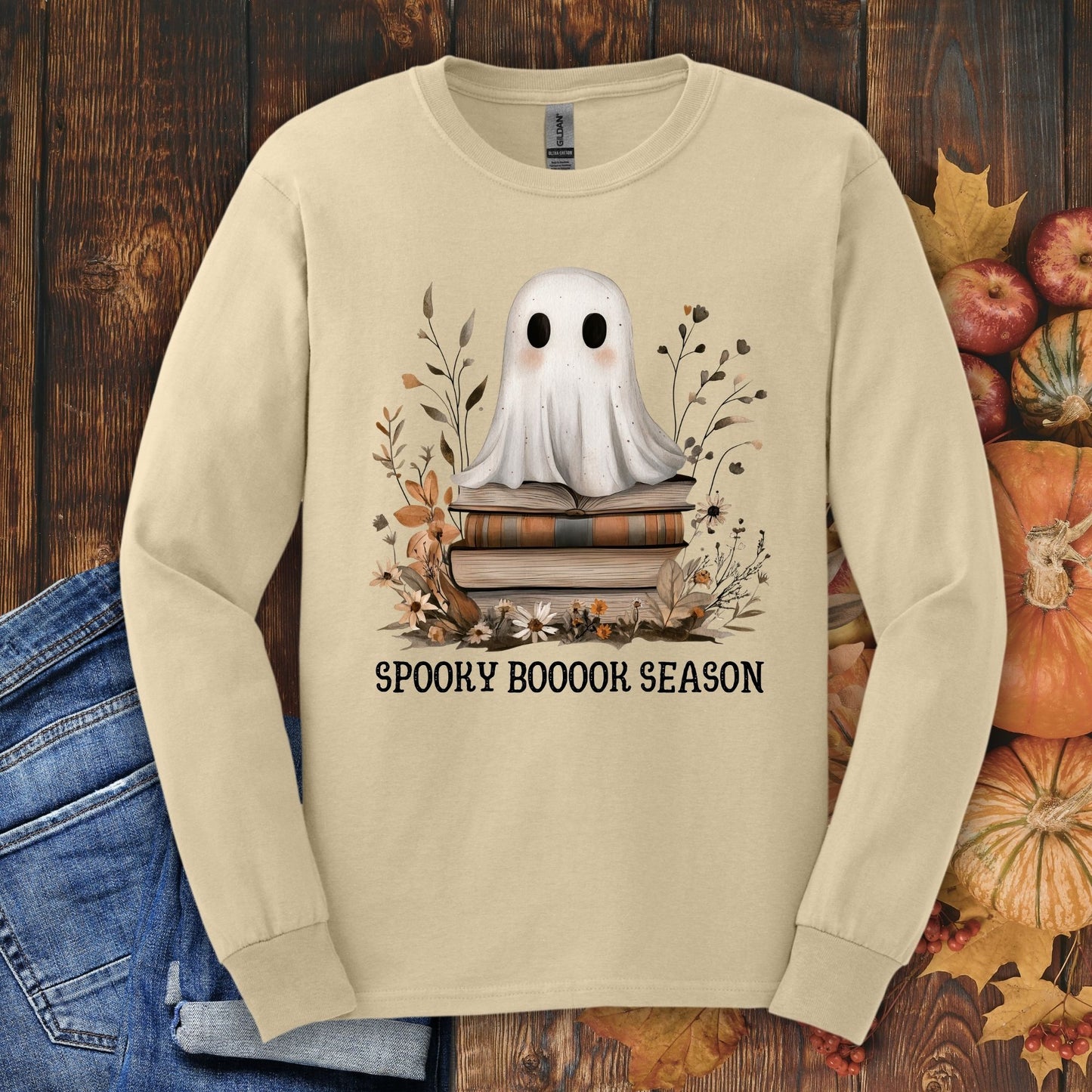 Sand long sleeve tee with a ghost on books, "Spooky Boooook Season" text, and fall foliage.