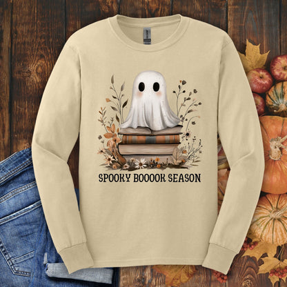 Sand long sleeve tee with a ghost on books, "Spooky Boooook Season" text, and fall foliage.