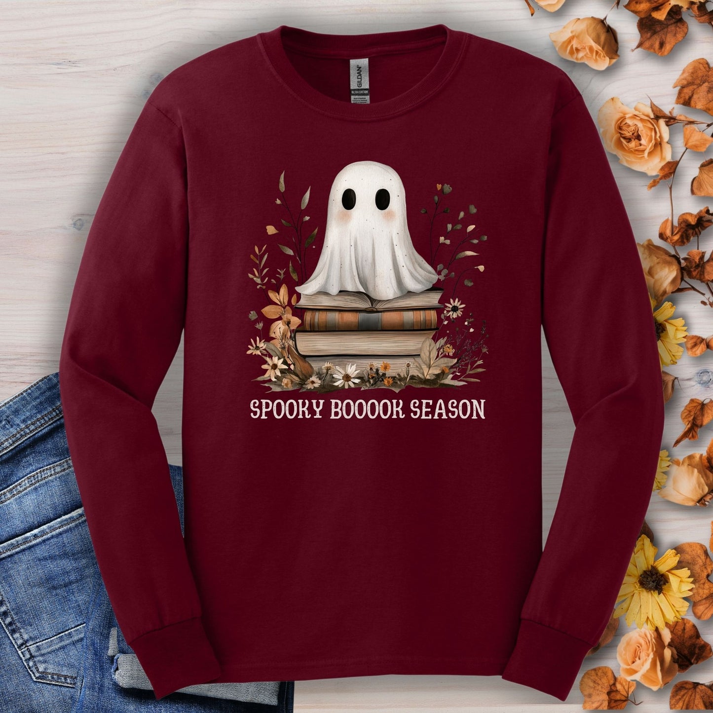 Maroon Gildan long sleeve tee with a boho ghost on books, fall wildflowers, and "Spooky Boooook Season" text.