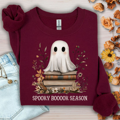 Maroon Gildan sweatshirt with a boho ghost on vintage books, surrounded by autumn wildflowers and "Spooky Booook Season" text.