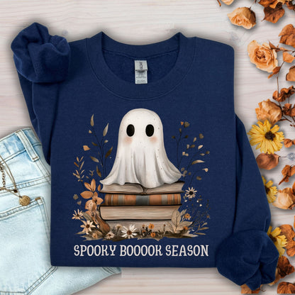 Navy Gildan sweatshirt with a boho ghost on vintage books, surrounded by autumn wildflowers and "SPOOKY BOOOOK SEASON" text.