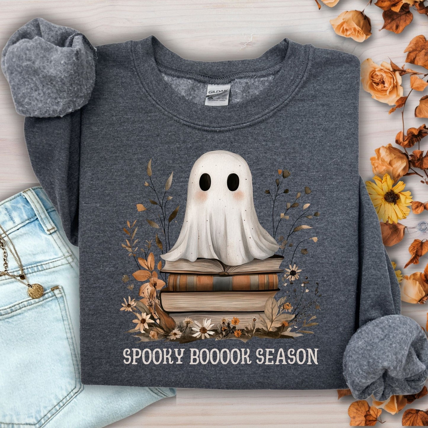 Dark Heather Gildan sweatshirt with a boho ghost on vintage books, surrounded by autumn wildflowers.