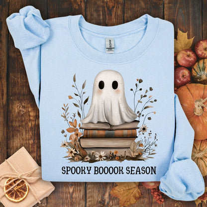 Light blue Gildan sweatshirt with a boho ghost on vintage books, surrounded by autumn wildflowers and "SPOOKY BOOOOK SEASON" text.