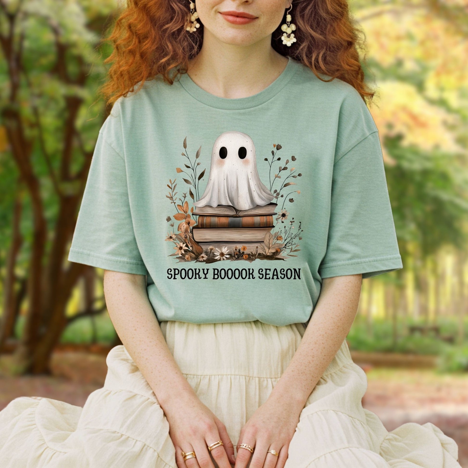 Mint green tee with a boho ghost on vintage books and "Spooky Boooook Season" text.