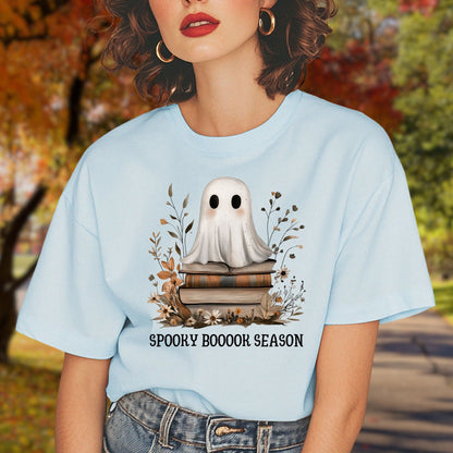 Light blue tee with a whimsical ghost on vintage books, surrounded by fall foliage, text "SPOOKY BOOOOK SEASON".