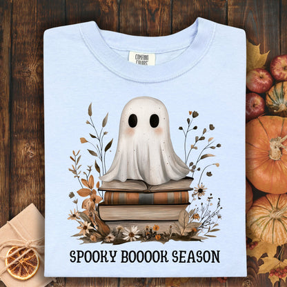 Hydrangea blue tee with a cute ghost on vintage books, surrounded by autumn foliage and "Spooky Boooor Season" text.