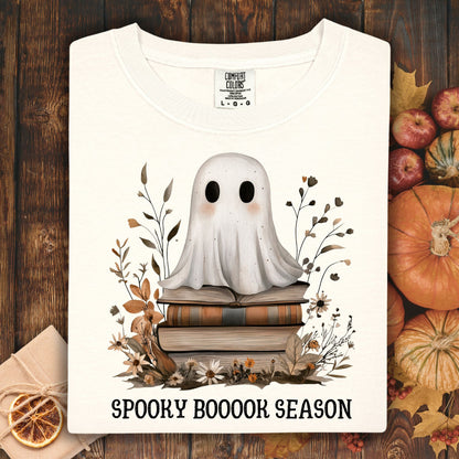 Ivory Comfort Colors tee with a cute ghost on vintage books, surrounded by autumn foliage and "Spooky Boooook Season" text.