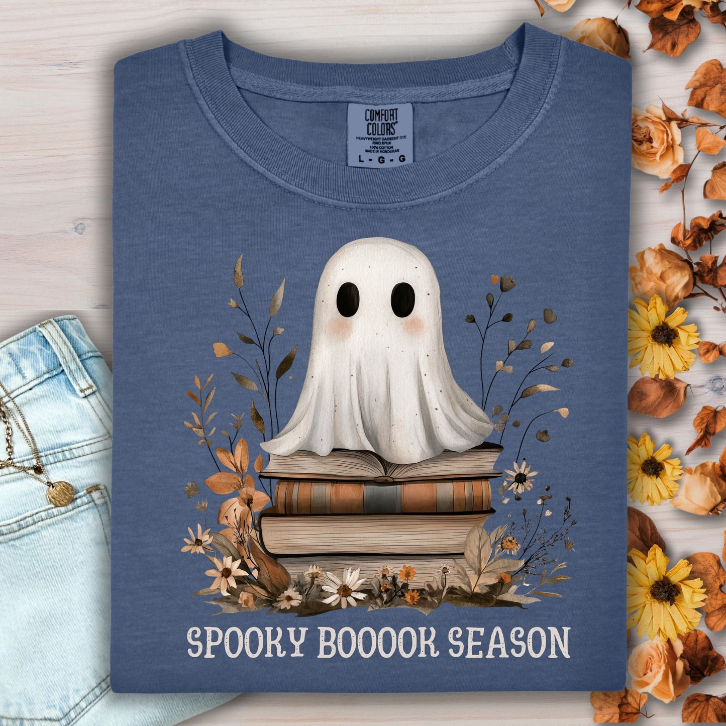 Denim blue "Spooky Book Season" tee with a whimsical ghost on vintage books and fall florals.