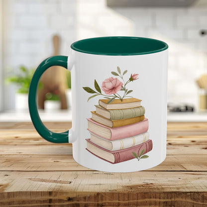 White ceramic mug with a green handle and interior, featuring a watercolor stack of books and pink floral accents.
