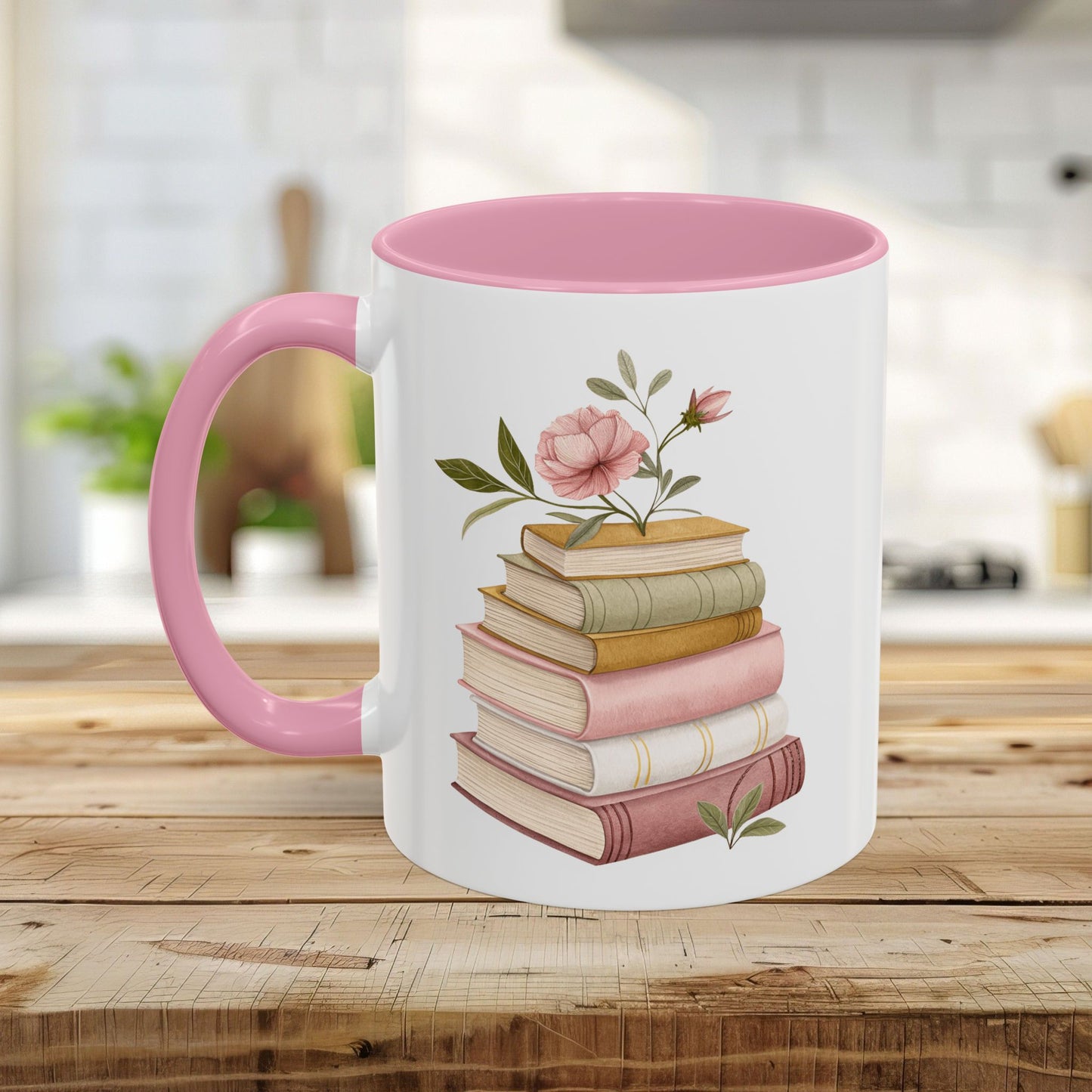 White ceramic mug with pink handle and interior, featuring a watercolor stack of books and floral design.