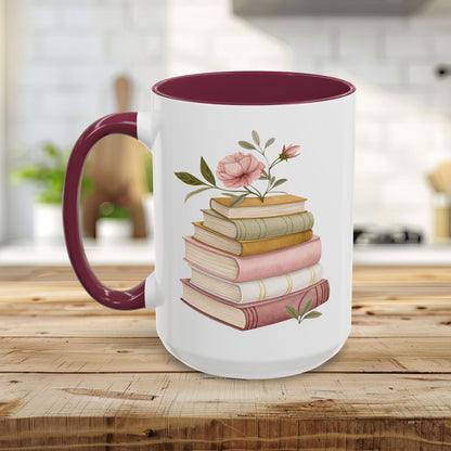 White ceramic mug with a maroon handle and interior, featuring a watercolor stack of books with pink floral accents.