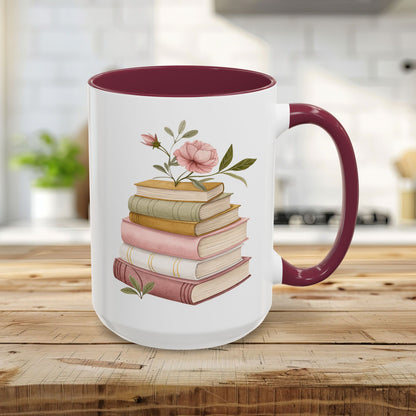 15oz glossy ceramic mug with a maroon handle and interior, featuring a watercolor stack of books with pink floral accents.