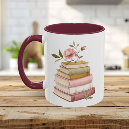 White ceramic mug with a burgundy handle and interior, featuring a watercolor stack of books and pink floral accents.