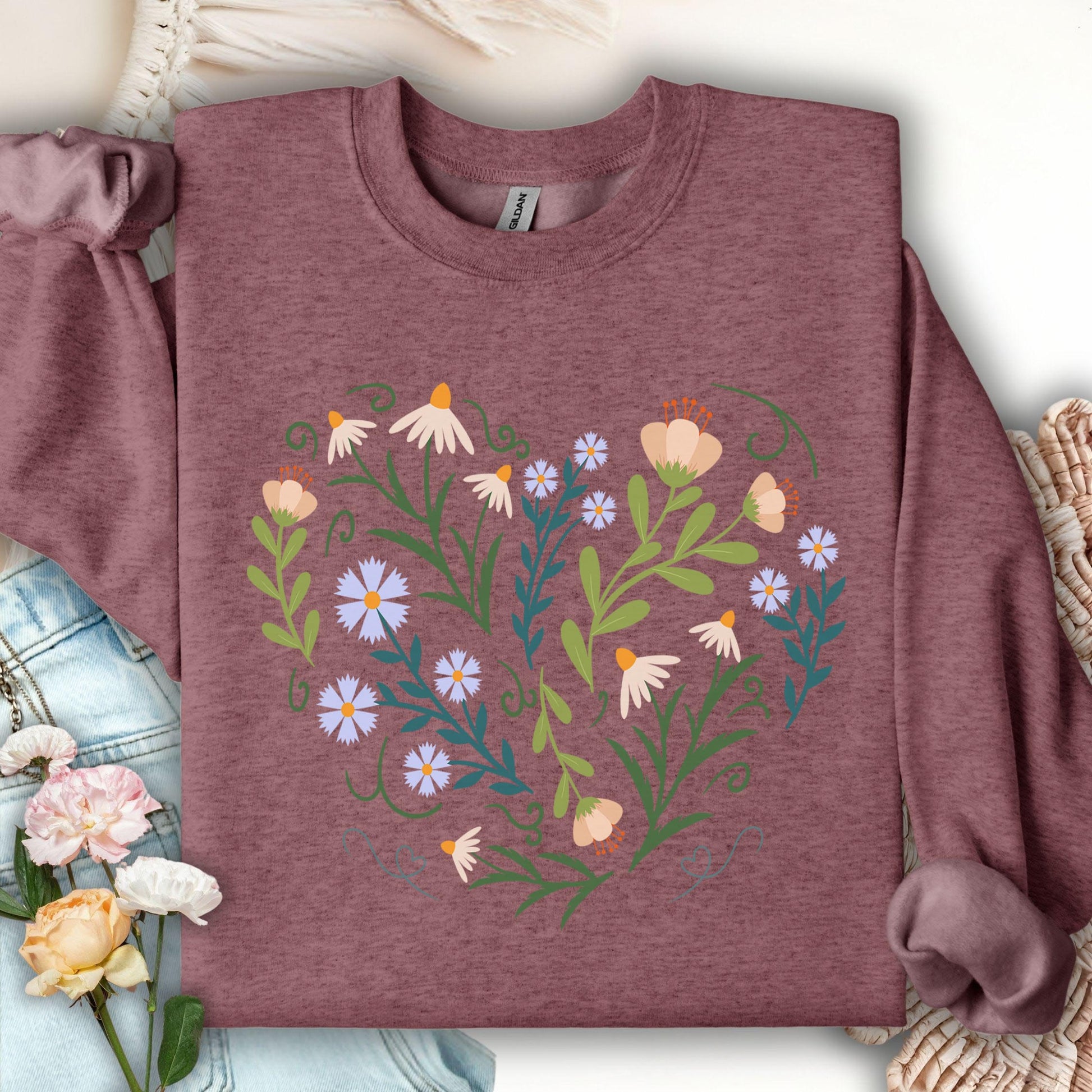 Maroon sweatshirt with a heart-shaped floral design of daisies, tulips, and bell flowers with green vines.