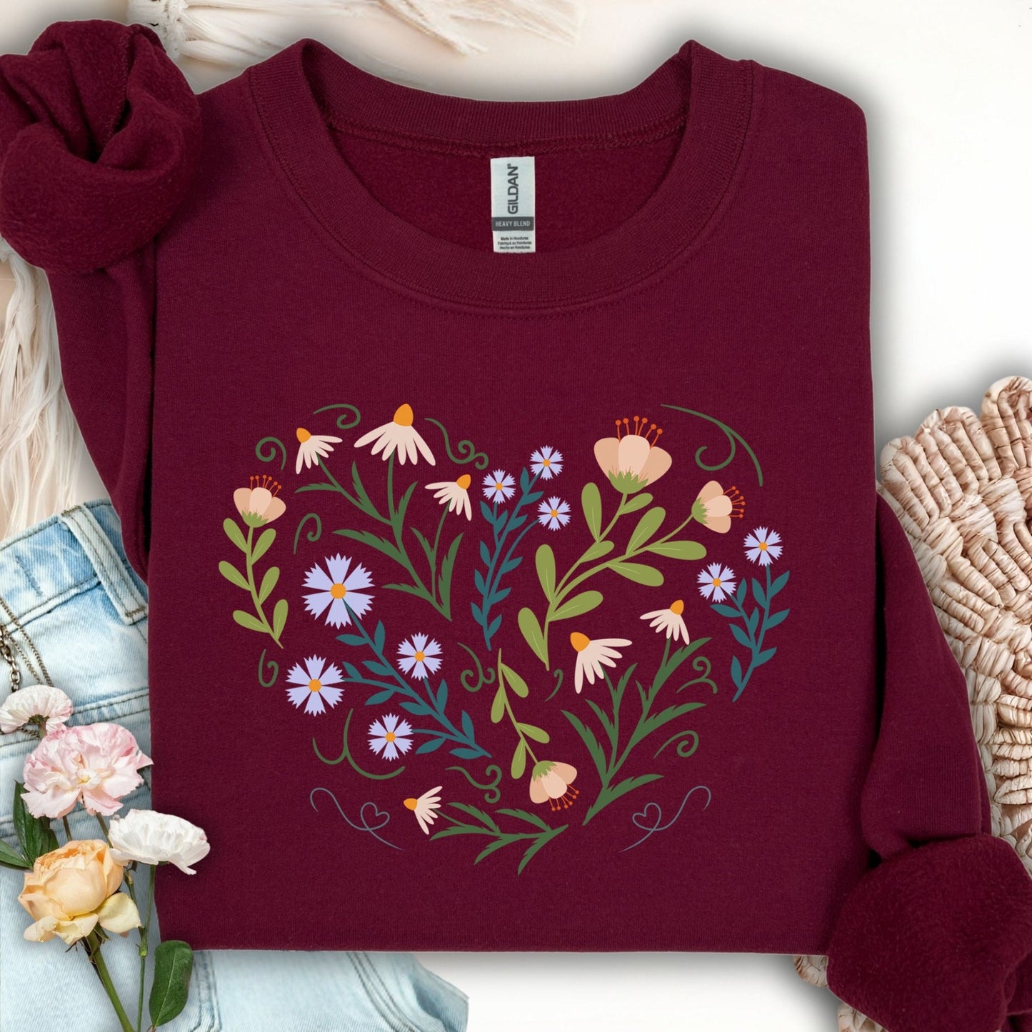 Maroon sweatshirt with a heart-shaped botanical illustration of wildflowers, leaves, and vines.