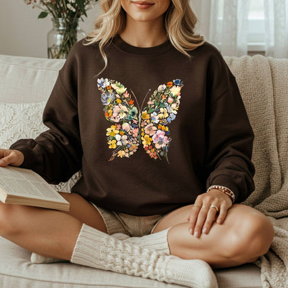 Woman in a brown sweatshirt with a colorful, symmetrical floral butterfly design, holding a book.