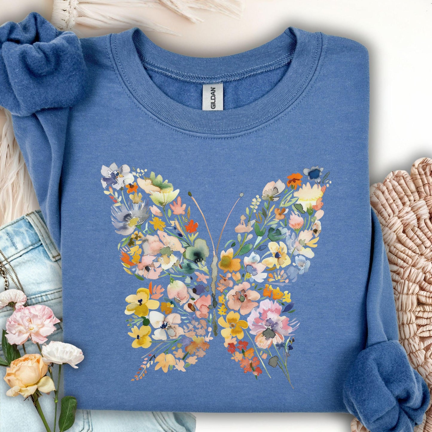 Indigo blue sweatshirt with a colorful floral butterfly design made of daisies and wildflowers.