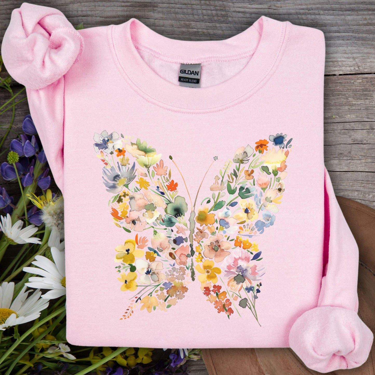 Light pink Gildan sweatshirt with a watercolor floral butterfly design, surrounded by wildflowers.