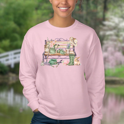 Pink long sleeve tee with a watercolor garden bench, tools, flowers, and a rabbit design.