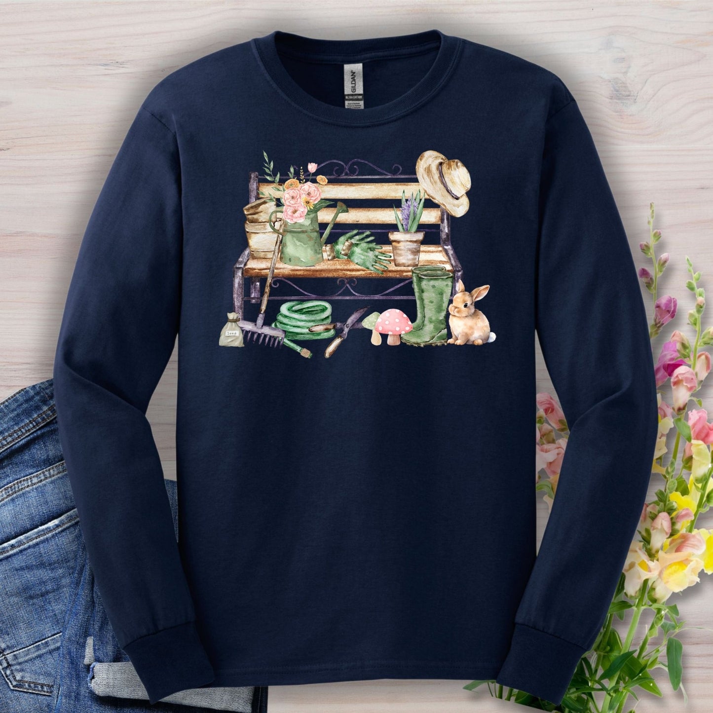 Navy long sleeve tee with a watercolor garden bench, tools, flowers, and a rabbit.