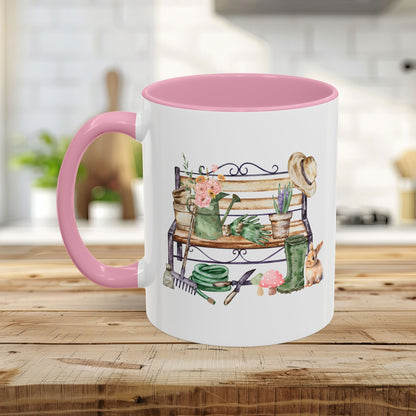 White ceramic mug with pink handle and interior, featuring a watercolor garden bench design.