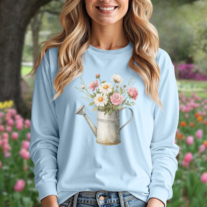 Woman in light blue long-sleeve tee with a vintage watering can and floral illustration.