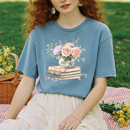Woman in blue t-shirt with watercolor pastel bouquet in vase on vintage books.
