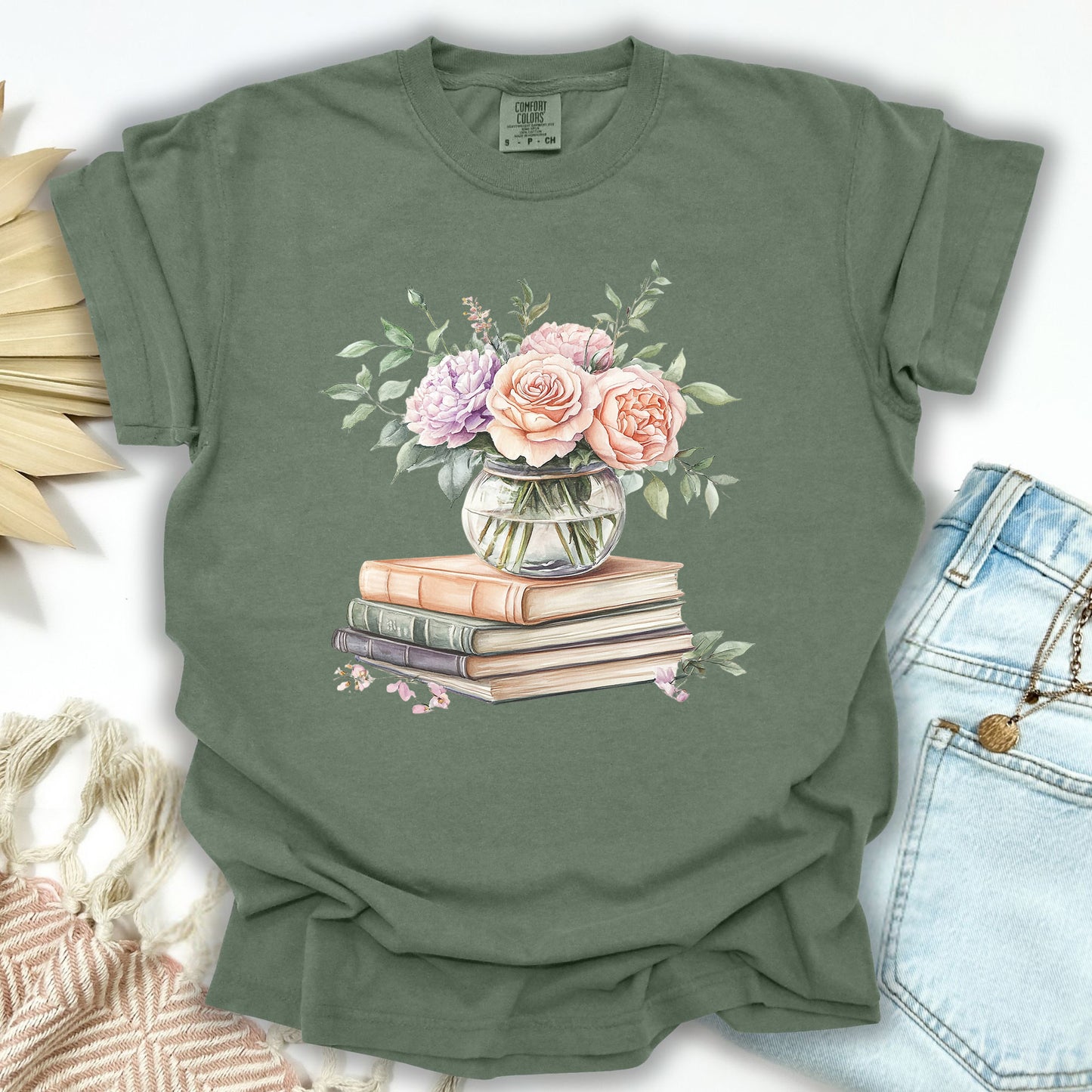 Moss S t-shirt with a watercolor bouquet in a glass vase on vintage books, scattered petals.