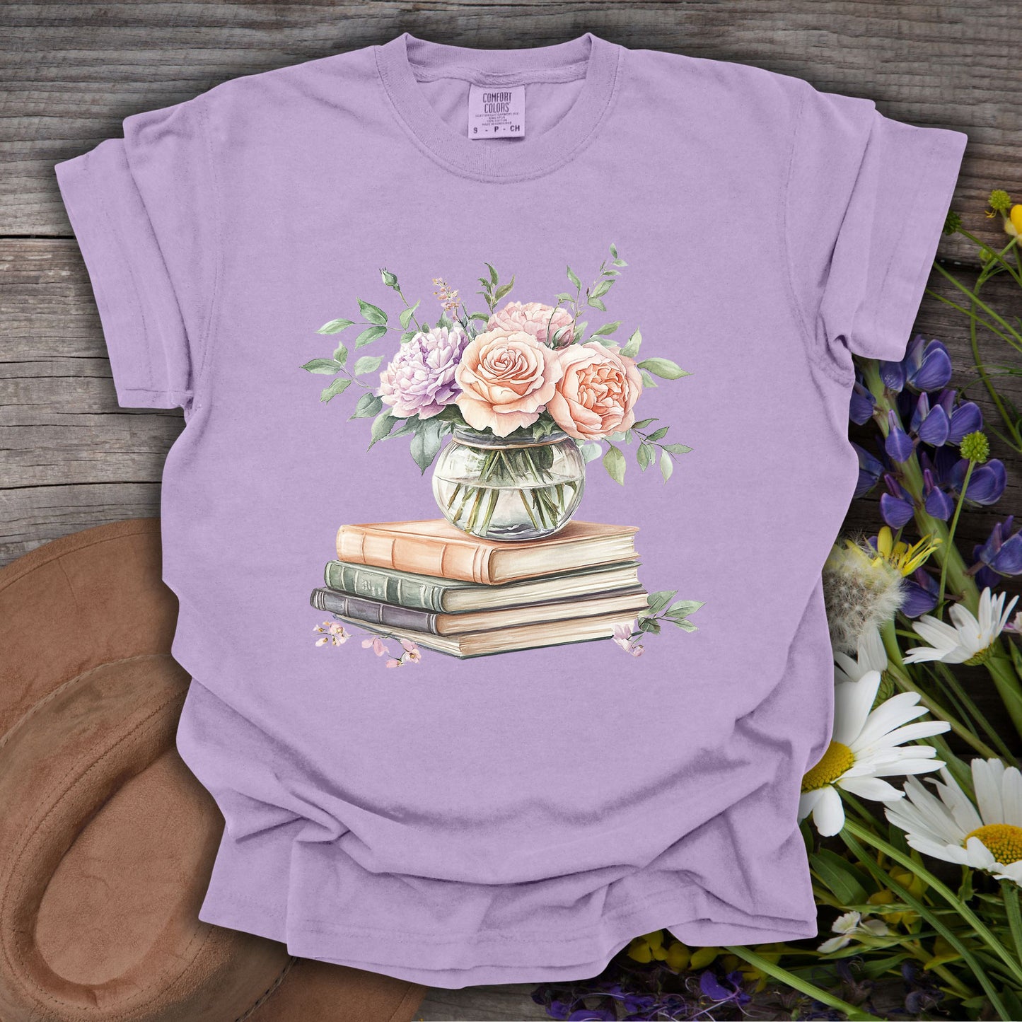 Orchid S t-shirt with a watercolor bouquet in a vase on vintage books, surrounded by wildflowers.