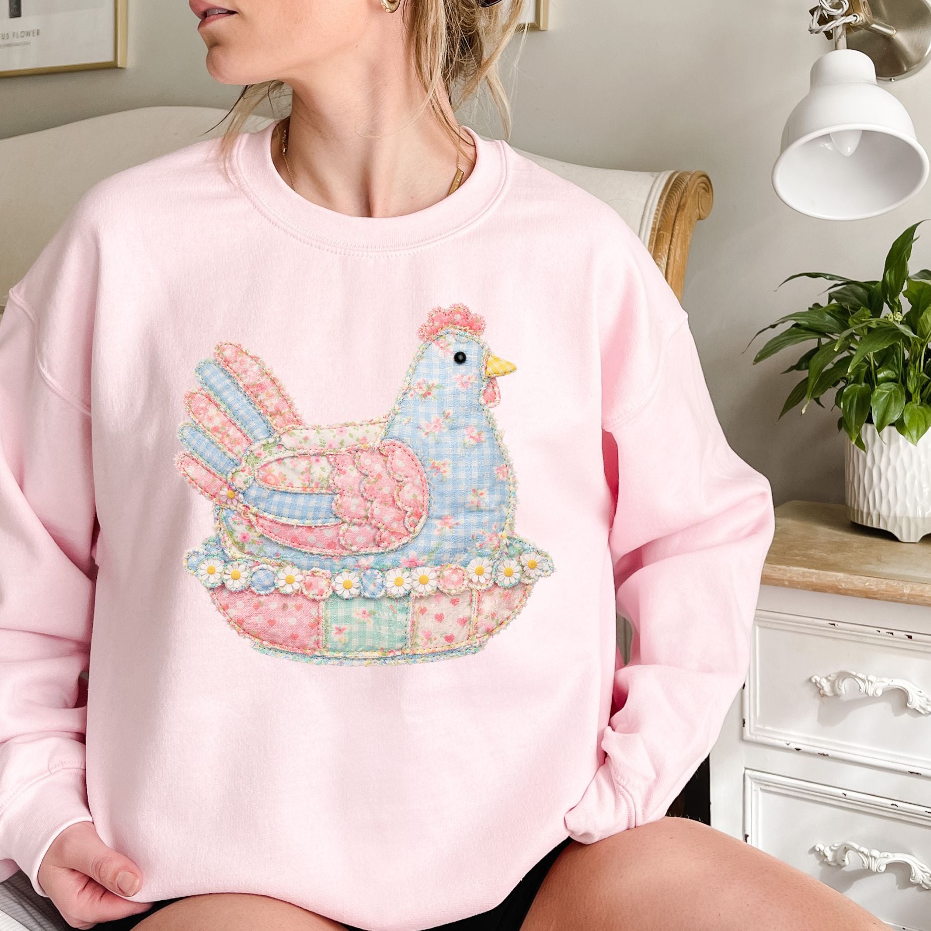 Pink crewneck sweatshirt with a pastel faux patchwork hen graphic in blue, pink, and green.