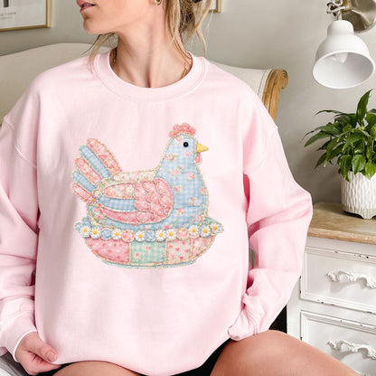 Pink crewneck sweatshirt with a pastel faux patchwork hen graphic in blue, pink, and green.