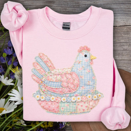 Light pink Gildan sweatshirt with a faux patchwork pastel hen graphic, surrounded by wildflowers.
