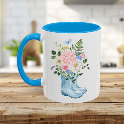 White ceramic mug with blue handle and interior, featuring a watercolor rain boot with a floral bouquet.