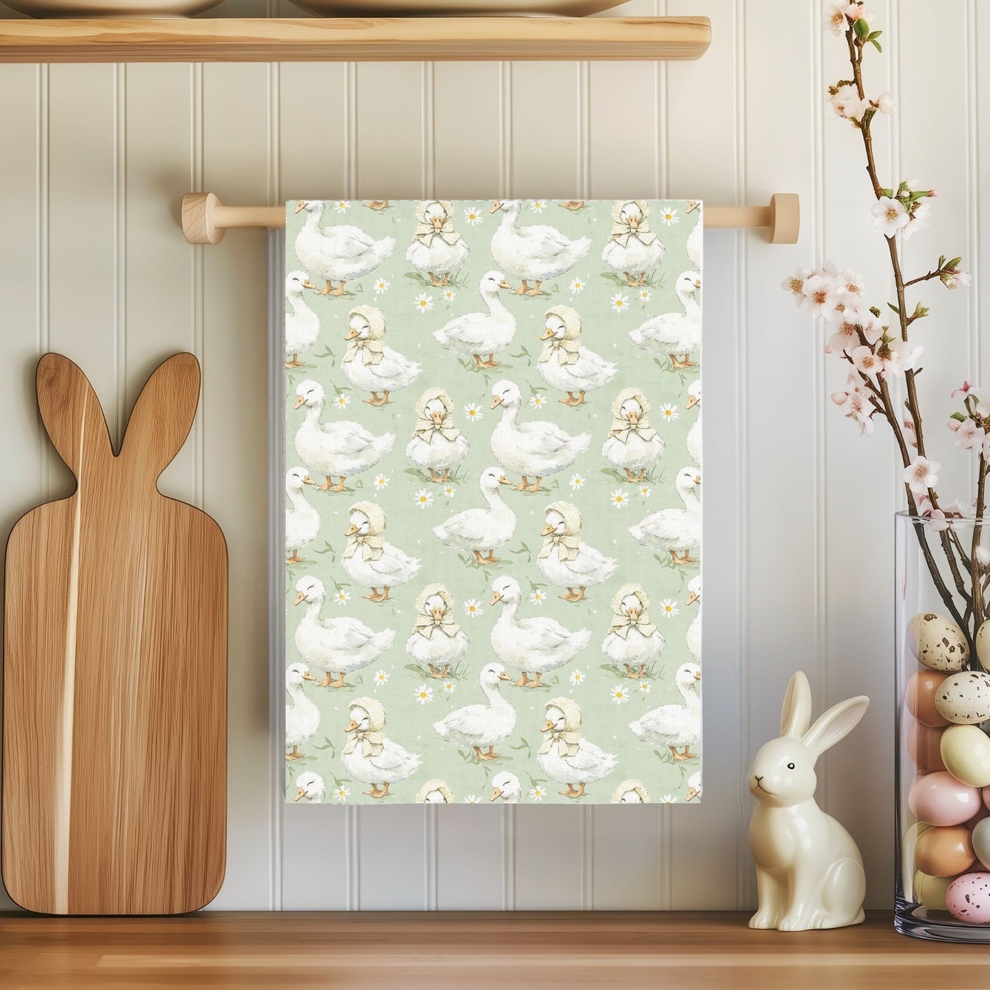 Microfiber tea towel with white ducks and ducklings on a sage background, hanging in a kitchen.