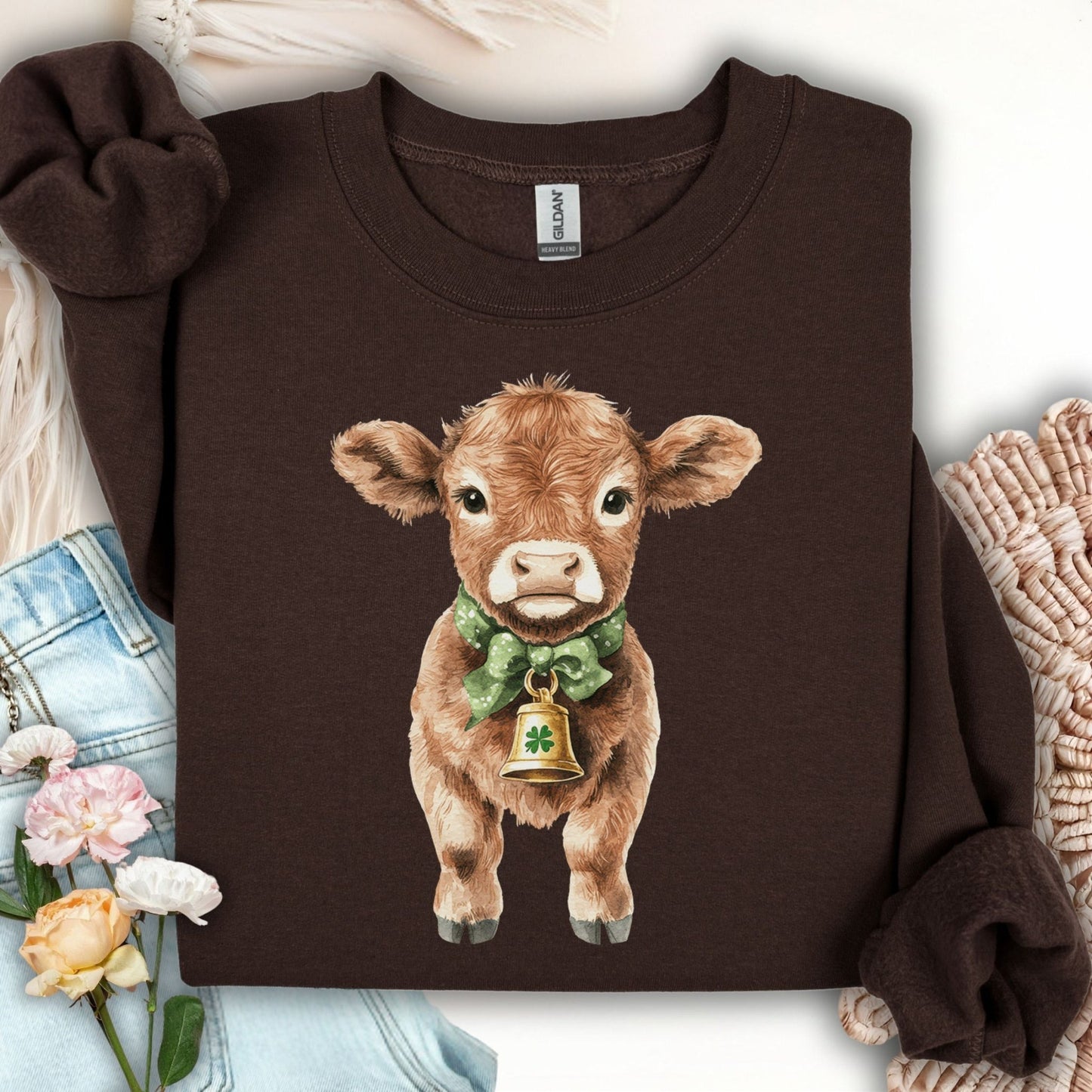 Dark chocolate unisex sweatshirt with a watercolor baby Highland cow, green bow, and clover bell.