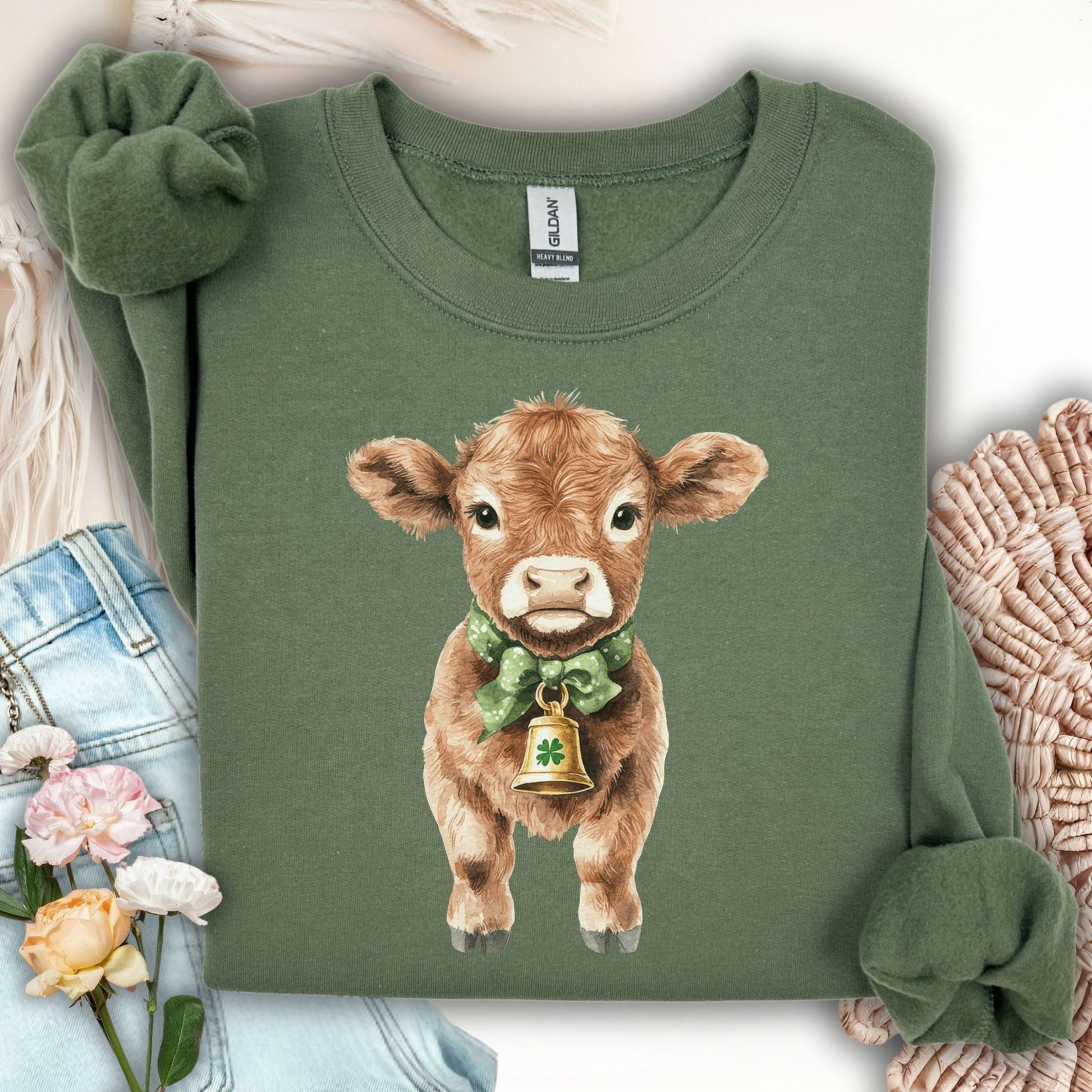Military green unisex sweatshirt with a watercolor baby Highland cow wearing a green bow and clover bell.