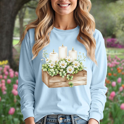 Light blue long sleeve tee with a watercolor wooden planter, daisies, candles, and four-leaf clovers.