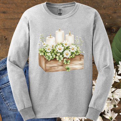 Ash long-sleeve tee with a watercolor clover planter, daisies, baby's breath, and three lit candles.
