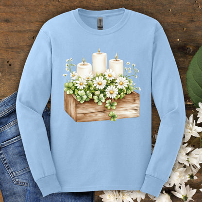 Light blue long sleeve tee with a watercolor clover planter, daisies, baby's breath, and three lit candles.