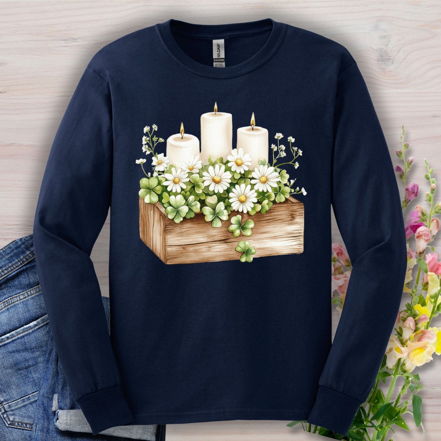 Navy long sleeve tee with a watercolor wooden planter, daisies, lit candles, and four-leaf clovers.