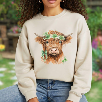 Beige sweatshirt with watercolor Highland cow wearing clover garland and bow.