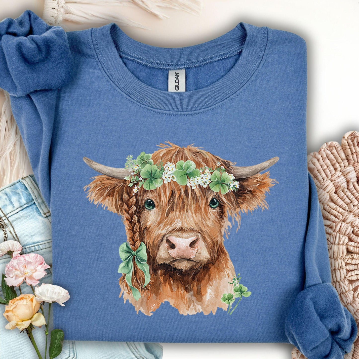 Indigo blue Highland cow sweatshirt with clover garland and bow.